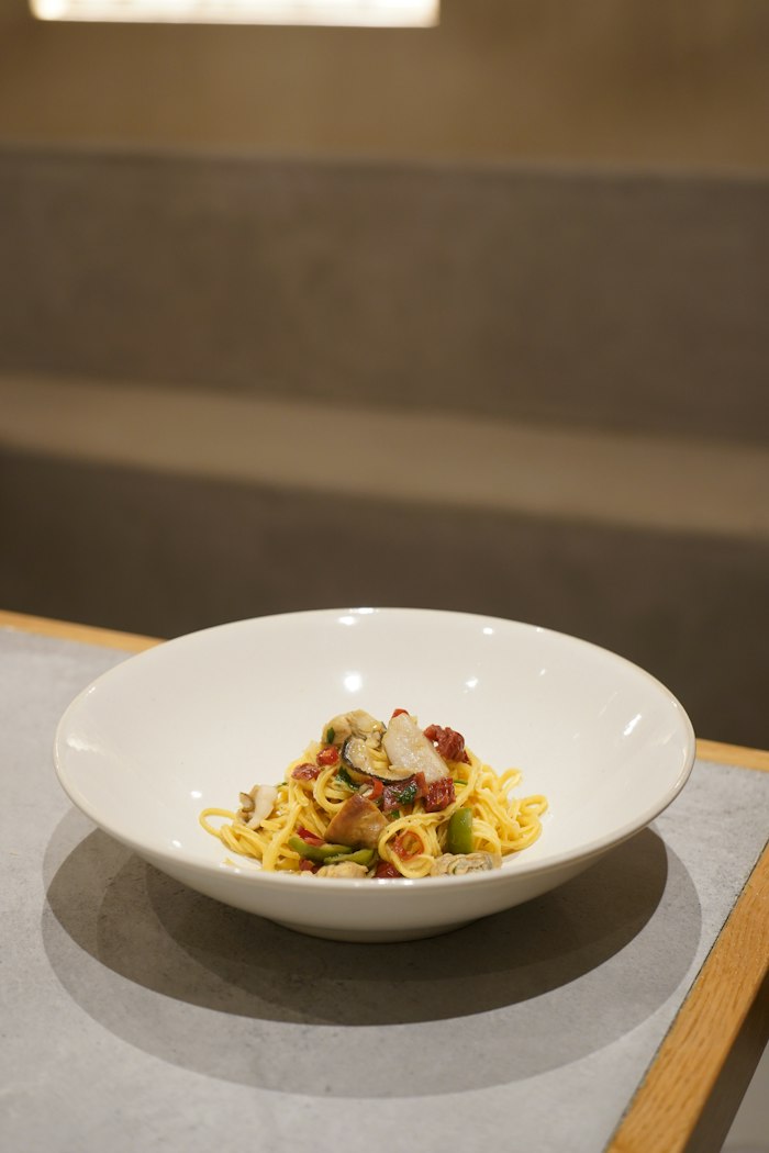旬の具材を合わせたパスタを白い器に盛り付けたひと皿